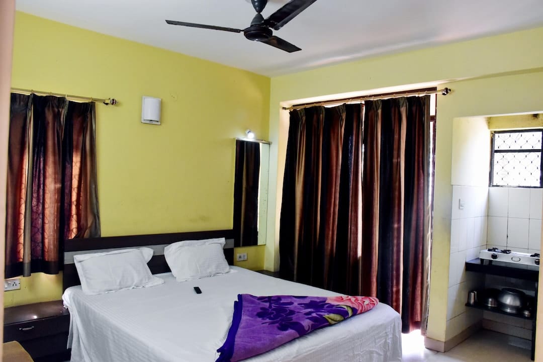 Family room at Hotel Nataraj Puri with double bed, tall curtained window and small kitchenette corner